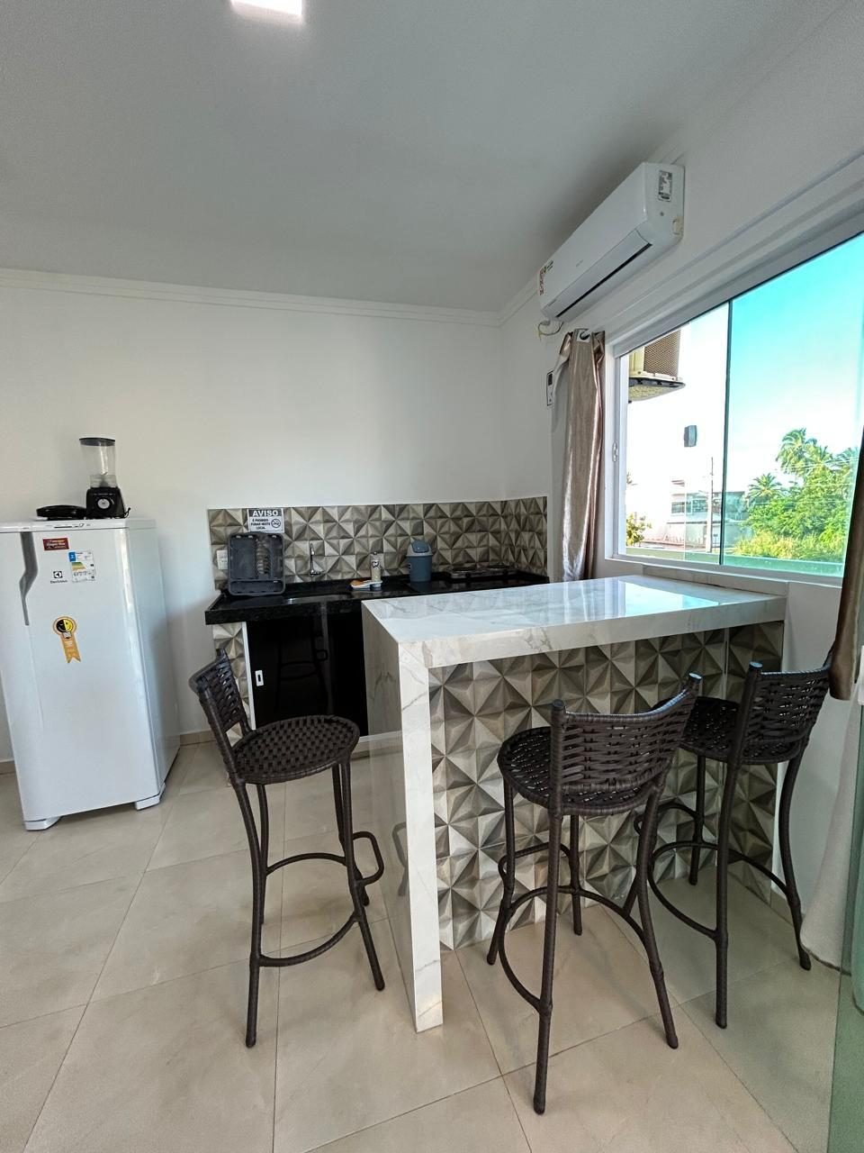 Cozinha do flat com bancada, banquetas e janela