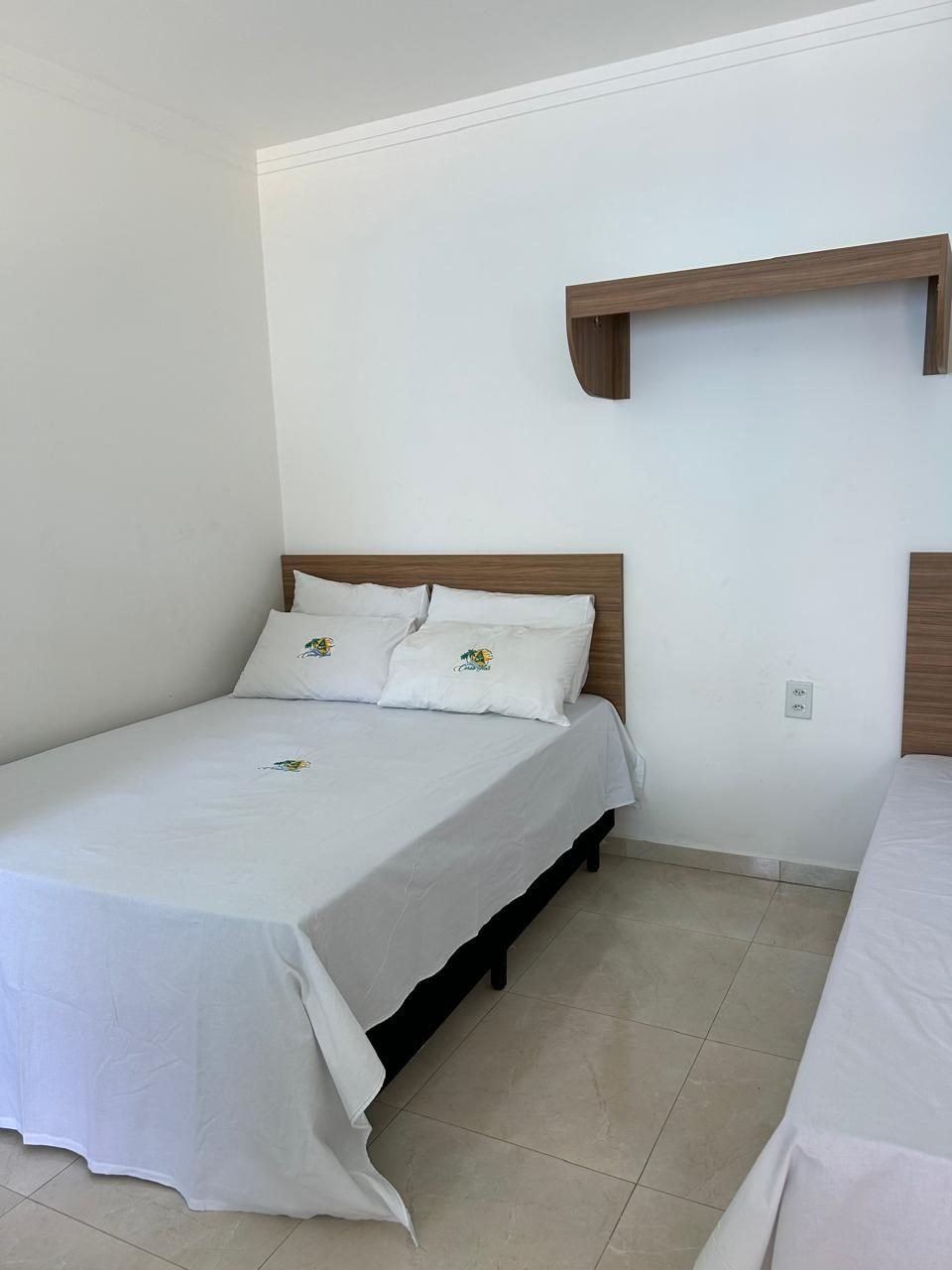 Quarto com cama de casal e roupa de cama bordada com a logo
